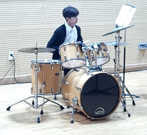 Yunwoo playing drums at a school music performance