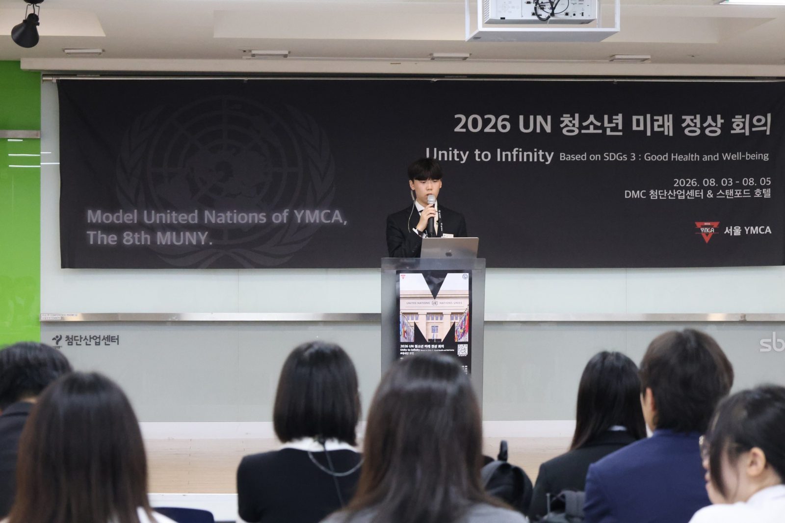 Delegates listening as Yunwoo addresses the summit